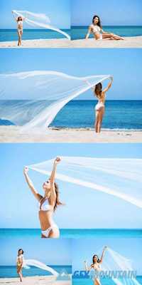 Young, Sporty and Happy Woman Posing with a Blowing Silk on a Summer Beach